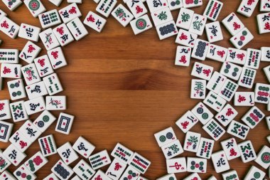 Mahjong kahverengi ahşap arka plan üzerinde beyaz-yeşil çini. Ortasındaki boş yer.