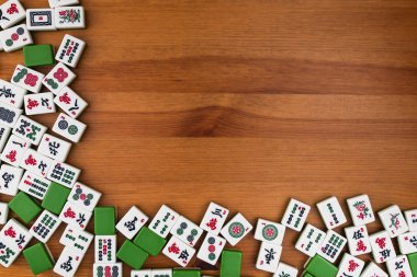 Mahjong kahverengi ahşap arka plan üzerinde beyaz-yeşil çini. Sağ üst köşedeki boş yer