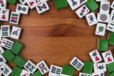 Mahjong kahverengi ahşap arka plan üzerinde beyaz-yeşil çini. Ortasındaki boş yer.