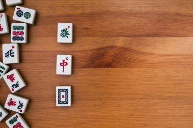 Mahjong kahverengi ahşap arka plan üzerinde beyaz-yeşil çini. Ortasındaki boş bir yer. 3 Ejder (kırmızı, beyaz, yeşil)