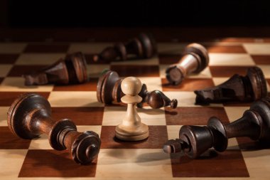 Satranç. Yalancı siyah rakamlar arasında bir satranç tahtası üzerinde beyaz piyon duruyor.