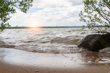 Dalga kumlu kıyıya atılıyor. Günbatımı