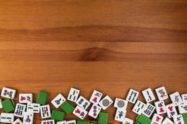Mahjong kahverengi ahşap arka plan üzerinde beyaz-yeşil çini. Boş alanı yukarıdaki