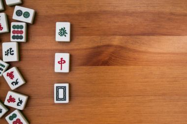 Mahjong kahverengi ahşap arka plan üzerinde beyaz-yeşil çini. Ortasındaki boş bir yer. 3 Ejder (kırmızı, beyaz, yeşil)