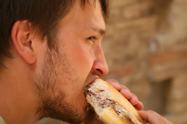 Homem Barbudo Come Sanduíche Com Carne Com Apetite — Fotografia de Stock