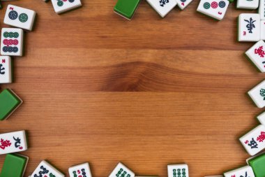 Mahjong kahverengi ahşap arka plan üzerinde beyaz-yeşil çini. Ortasındaki boş yer.