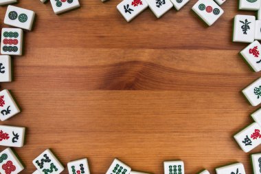 Mahjong kahverengi ahşap arka plan üzerinde beyaz-yeşil çini. Ortasındaki boş yer.