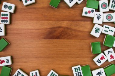 Mahjong kahverengi ahşap arka plan üzerinde beyaz-yeşil çini. Ortasındaki boş yer.