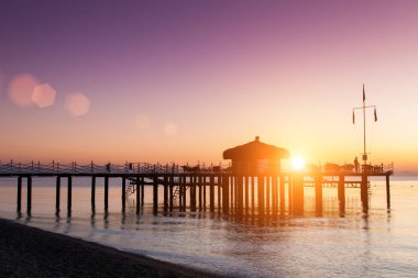 Bungalov pier üzerine güneş ışığı ile sular altında olduğunu. Leylak şafak gökten.
