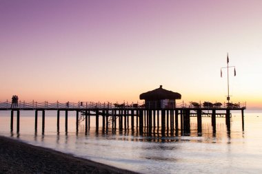 Bungalov pier üzerine güneş ışığı ile sular altında olduğunu. Leylak şafak gökten.