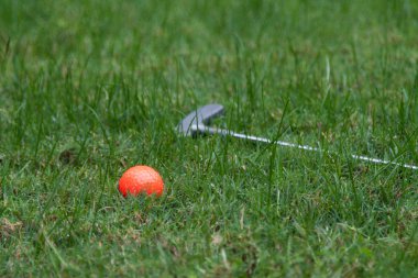 Turuncu golf topu ve atıcı yeşil çimenlerin üzerinde
