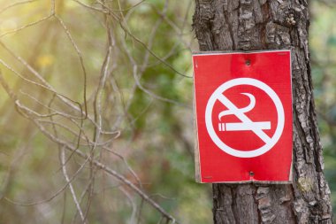 Bir çapraz duman sigara ile kırmızı bir işaret (sigara yasaktır) bir ağaç gövde çivilenmiş