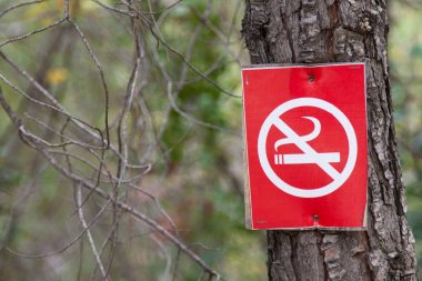Bir çapraz duman sigara ile kırmızı bir işaret (sigara yasaktır) bir ağaç gövde çivilenmiş