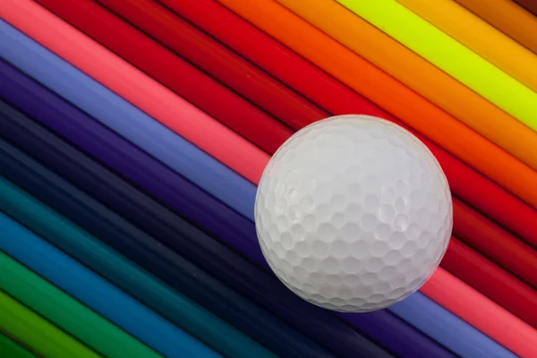 Détail du crayon coloré arc-en-ciel et de la balle de golf sur le bureau — Photo