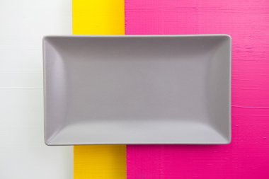 Boş gri seramik tabak üzerinde beyaz, sarı ve pembe ahşap üzerinde 