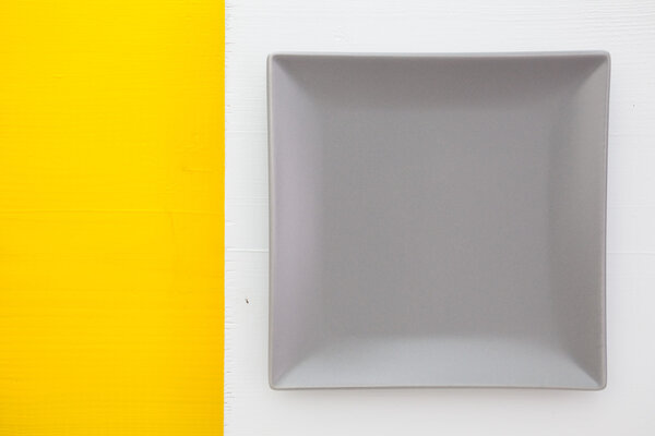 Empty gray ceramic dish on over white and yellow background, 