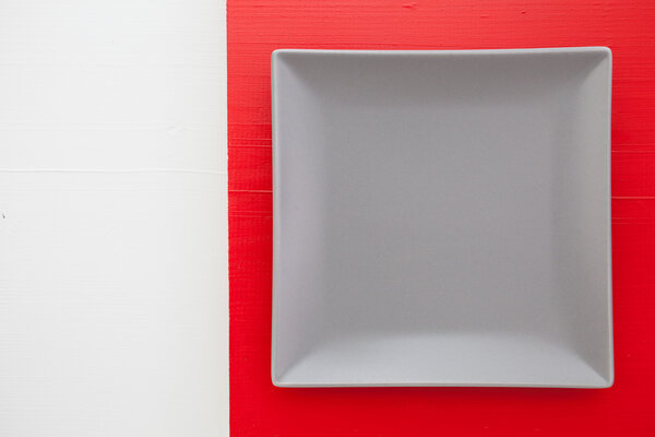 Empty gray ceramic dish on over red and white background