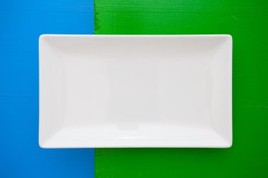 Empty white ceramic dish on over blue and green background, rect clipart