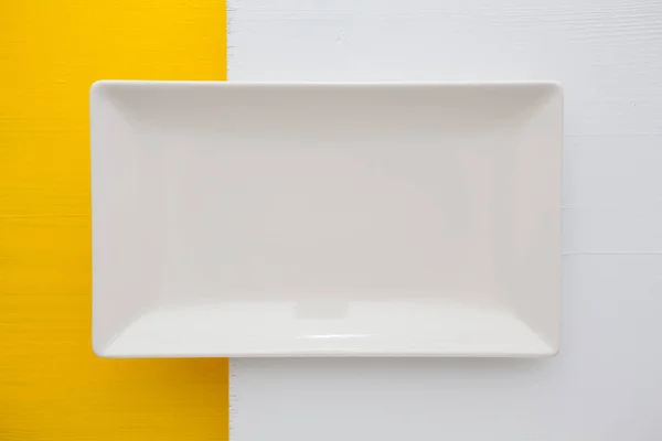 Boş beyaz seramik tabak üzerinde beyaz ve sarı bir arka plan üzerinde, — Stok fotoğraf