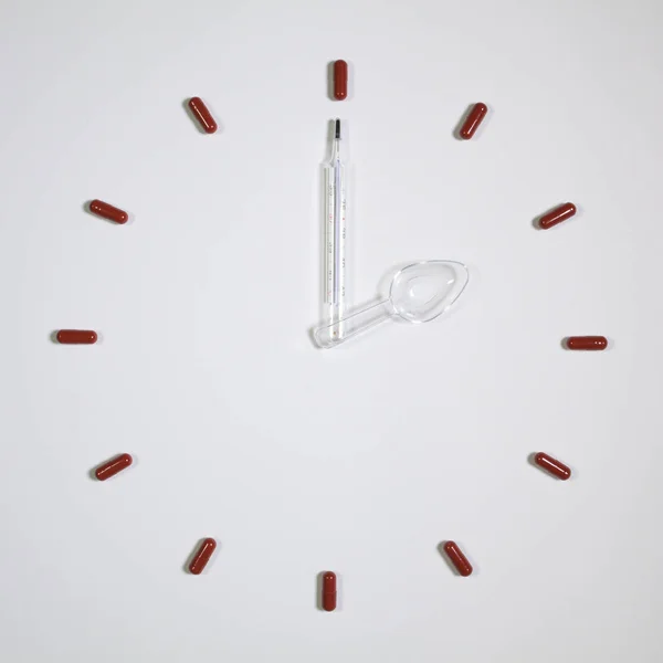 Годинник з дванадцяти таблеток, медичний термометр і пластикова ложка — стокове фото