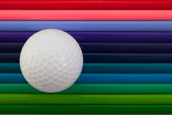 Detalhe do lápis colorido arco-íris e bola de golfe na mesa — Fotografia de Stock