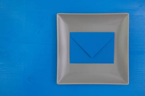 Gray ceramic dish with envelope on the wooden table, square  dis — Stock Photo, Image