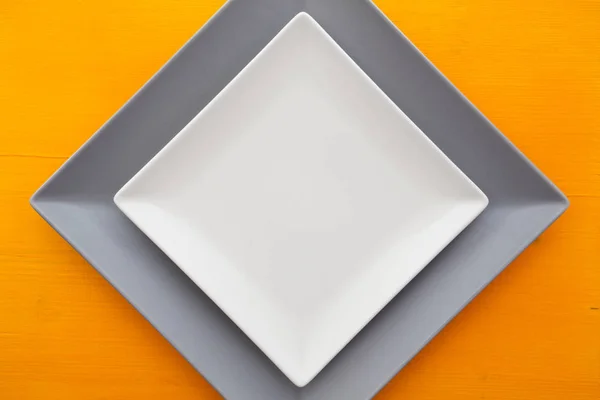 Plato de cerámica blanco vacío sobre mesa de madera naranja — Foto de Stock