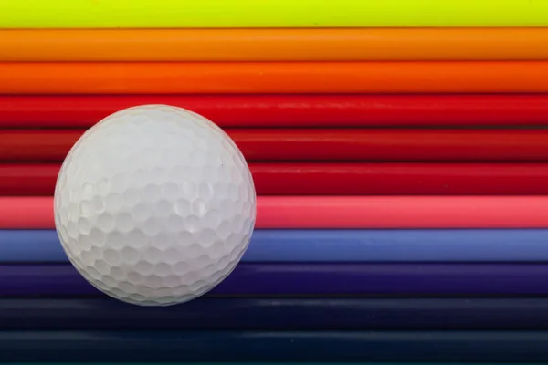 Dettaglio di matita colorata arcobaleno e pallina da golf sulla scrivania — Foto Stock