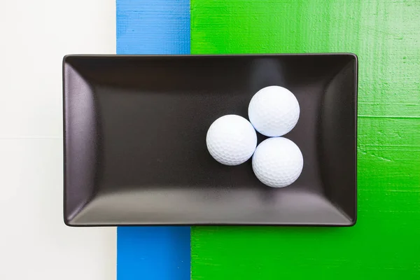 Black ceramic dish with golf balls — Stock Photo, Image