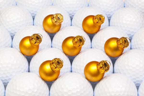 Золотое рождественское украшение между мячами для гольфа — стоковое фото