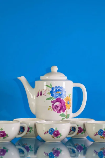 Molto vecchio tè di porcellana impostato su sfondo riflesso blu — Foto Stock