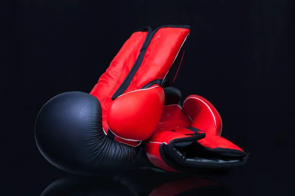 黑色玻璃桌上的红色和黑色拳击手套 — 图库照片
