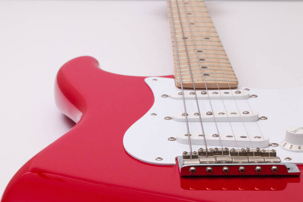 Detail of a red electric guitar on the white table
