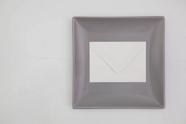 Серый керамическое блюдо с конвертом на деревянный стол, квадратный дис — стоковое фото
