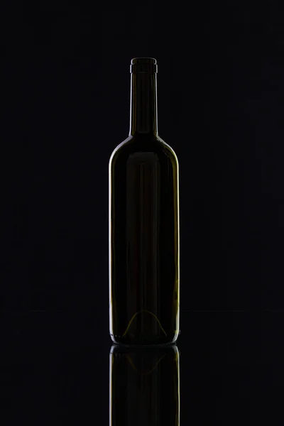 Силуэт элегантной и очень старой бутылки вина на стеклянном столе — стоковое фото