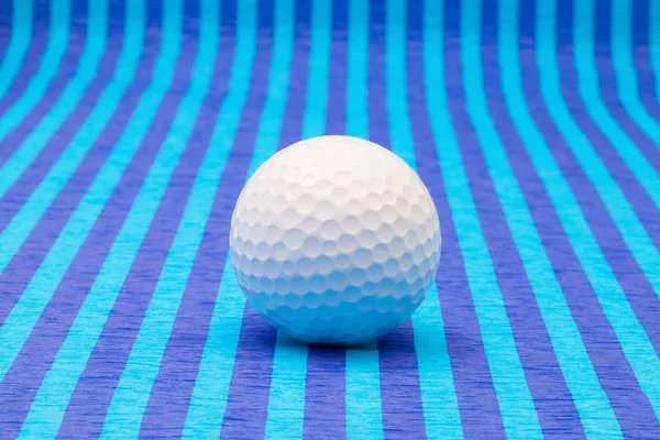 Weißer Golfball auf blau gestreiftem Tisch. — Stockfoto