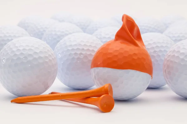 Белые мячи для гольфа с забавной шапкой на белом фоне . — стоковое фото