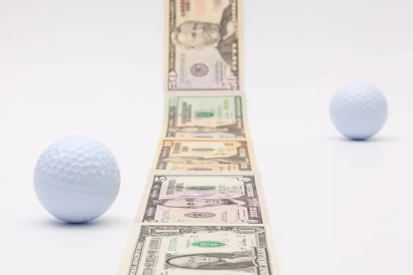 Tiras de diferentes billetes de dólar y pelota de golf blanca — Foto de Stock