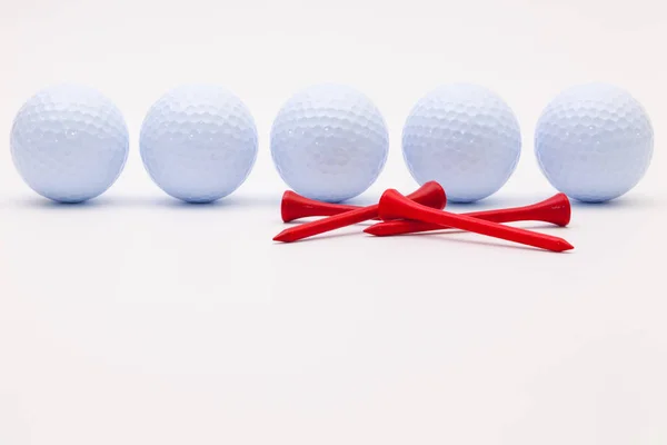 Bílé golfové míčky a dřevěné tees na bílém pozadí. — Stock fotografie