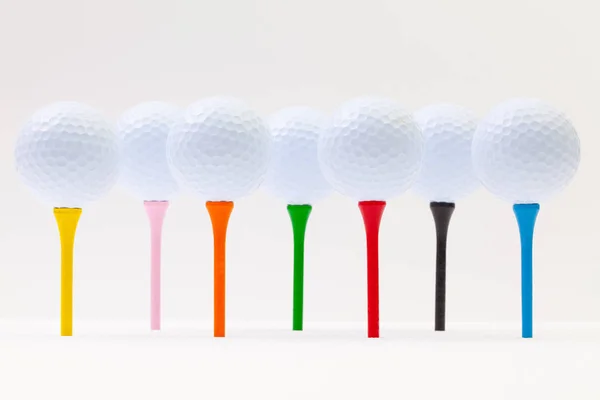 Bolas de golfe branco e T diferentes na mesa branca . — Fotografia de Stock