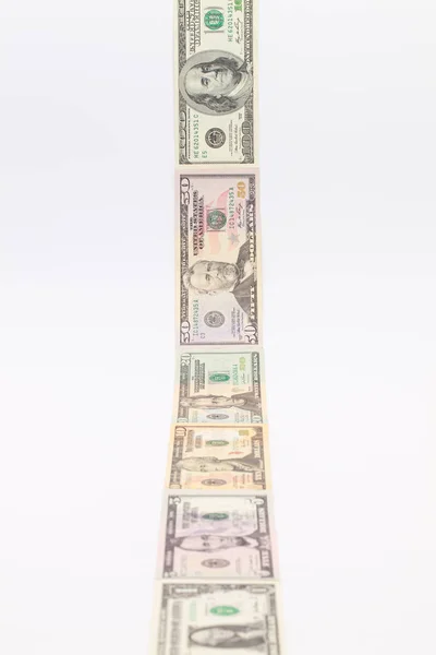 Franja de billetes de diferentes dólares estadounidenses en el escritorio blanco — Foto de Stock