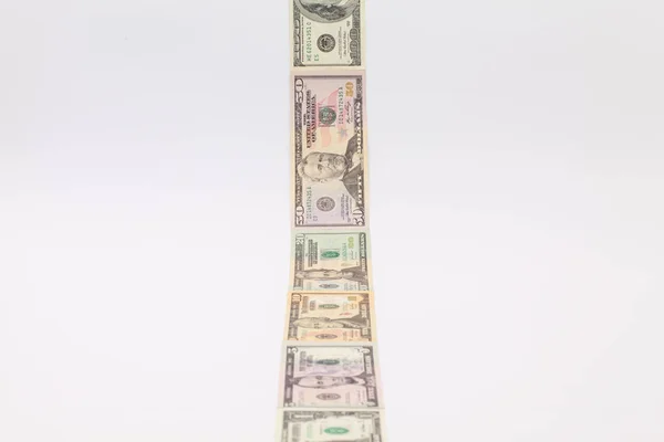 Strip of different us dollar banknotes on the white desk — Stock Photo, Image