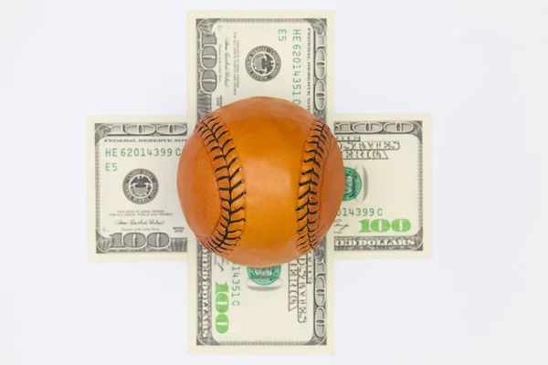 Pelota de béisbol de cuero y billetes en dólares . — Foto de Stock