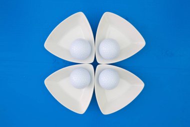 Beyaz golf topları üzerinde üçgen seramik kaseler 