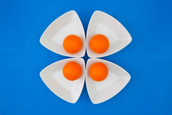 Oranžový golfové míčky na trojúhelníkové keramické misky — Stock fotografie