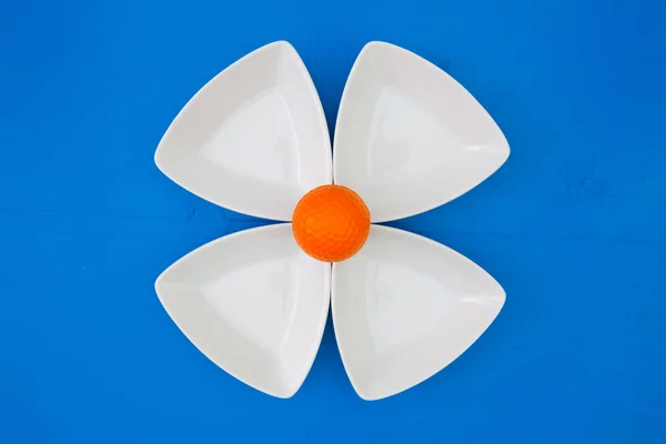 Orangefarbener Golfball auf den dreieckigen Keramikschalen — Stockfoto