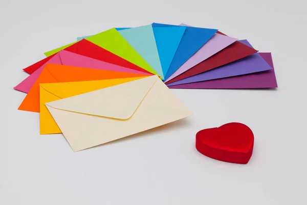 Enveloppes de différentes couleurs et coeur rouge — Photo