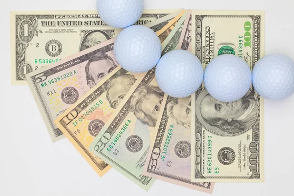 Białe piłeczki golfowe i różnych nas banknotów dolara. — Zdjęcie stockowe