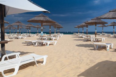 Satır şezlong ve şemsiyeleri sahilde. Tavira, Portekiz