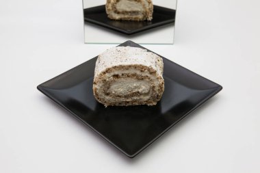 Tek parça ceviz rulo ile krem şanti bir siyah plaka üzerinde.